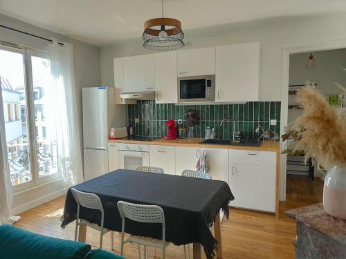 une cuisine avec des placards blancs et une table avec des chaises dans l'établissement Appartement calme et lumineux à Clichy, à Clichy