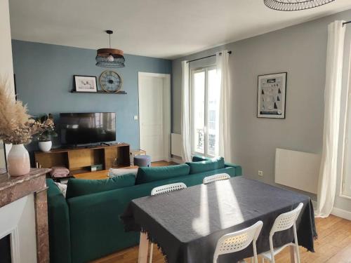 - un salon avec un canapé vert et une table dans l'établissement Appartement calme et lumineux à Clichy, à Clichy