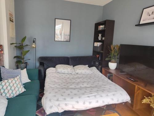 - une chambre avec un lit et un canapé bleu dans l'établissement Appartement calme et lumineux à Clichy, à Clichy