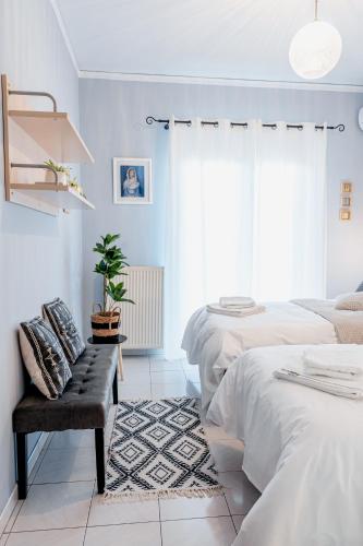 a white bedroom with two beds and a bench at Va Yia/ Spacious guest house in Nafplio