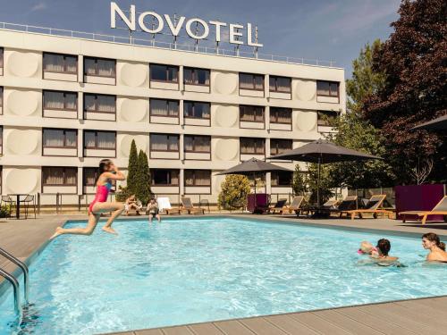 Eine Frau springt in einen Swimmingpool in einem Hotel. in der Unterkunft Novotel Nancy in Nancy