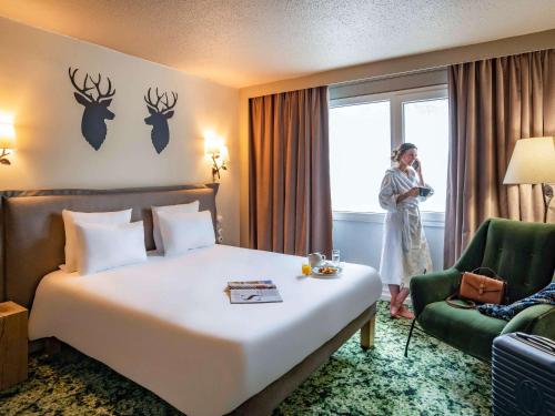 a woman standing next to a bed in a hotel room at Novotel Orléans Sud La Source in Orléans