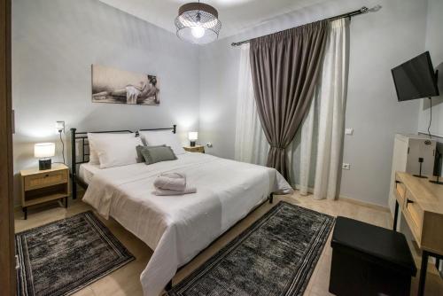 a bedroom with a large white bed and a television at Trikala Home in Tríkala
