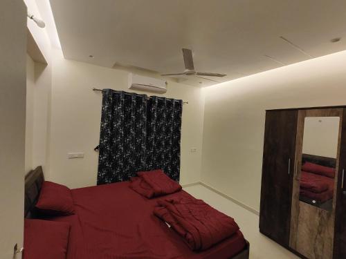 1 dormitorio con cama roja y ventana en Gandhi Villa, en Daman