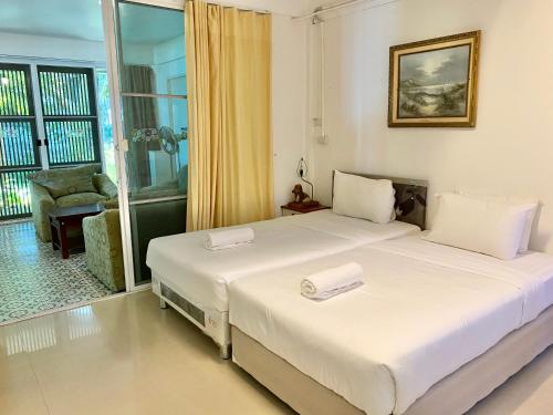 a bedroom with two beds and a window with a chair at Baan Napapan Beach Front, Hua Hin in Hua Hin