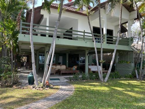 a house with palm trees in front of it at Baan Napapan Beach Front, Hua Hin in Hua Hin