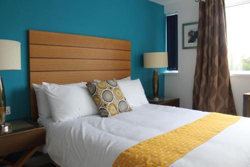 a bedroom with a large bed with a blue wall at Maze apartments and rooms in Hull