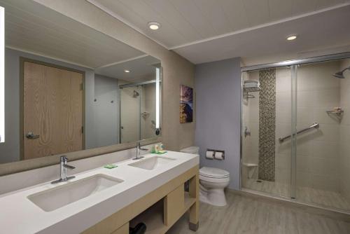 a bathroom with two sinks and a toilet and a mirror at Hyatt Place Managua in Managua