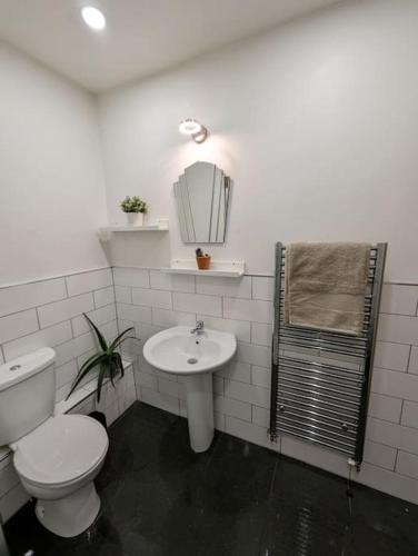 a white bathroom with a toilet and a sink at Bold street apartment in Liverpool