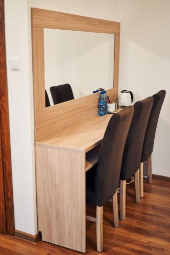 a wooden table with black chairs and a mirror at Hotel Lilia in Włoszczowa