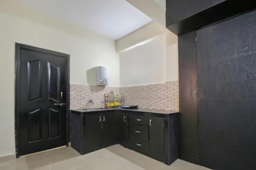 a kitchen with black cabinets and a black door at APERTEMEN PERMATA INDAH in Kotabatu