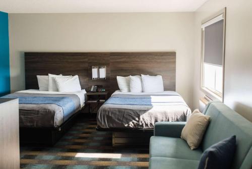 a hotel room with two beds and a couch at Travelodge by Wyndham Escanaba in Escanaba