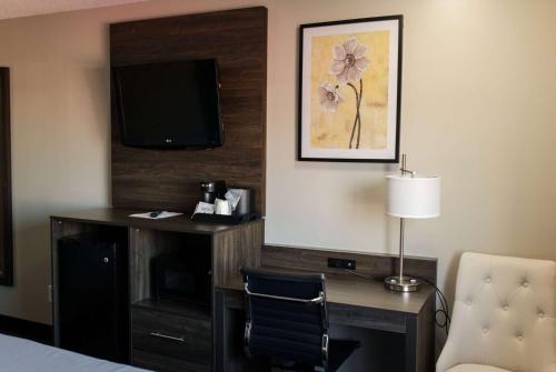 a hotel room with a desk with a tv and a chair at Travelodge by Wyndham Escanaba in Escanaba