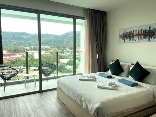um quarto com uma cama grande e uma janela grande em Sea view apartment at Oceana by Lofty em Kamala Beach