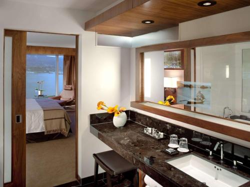 uma casa de banho com um lavatório, um espelho e uma cama em Fairmont Pacific Rim em Vancouver