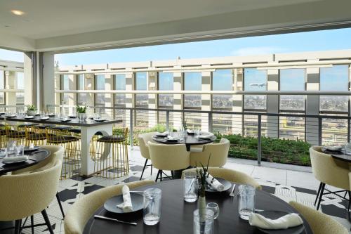 洛杉磯的住宿－Hyatt Place LAX/Century BLVD，餐厅设有桌椅和大窗户。
