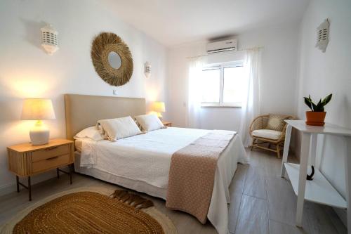 a white bedroom with a bed and a window at Casa Duarte in Carvoeiro