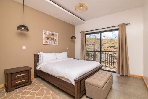 ein Schlafzimmer mit einem Bett und einem großen Fenster in der Unterkunft Tulia Villas, 3 and 4 bedroom Villas, Champagne Ridge in Kajiado