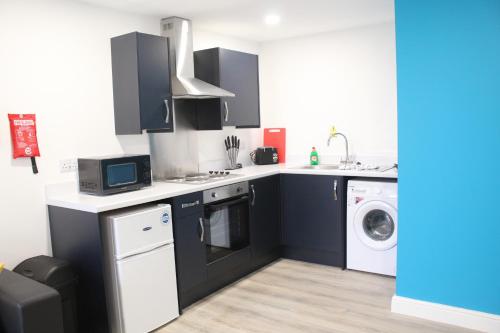 a kitchen with black cabinets and a washer and dryer at Maze apartments and rooms Free parking in Hull