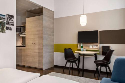 a room with a table and chairs and a tv at Vienna House Easy by Wyndham Osnabrück City & Apartments in Osnabrück