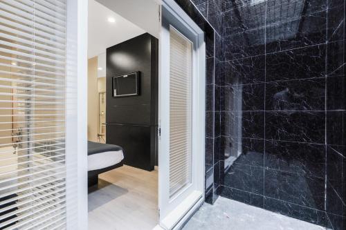 a bathroom with a shower with black tiles at Studio Flat West End Lane in London