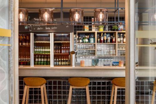 a bar with two stools and bottles of alcohol at Vienna House Easy by Wyndham Osnabrück City & Apartments in Osnabrück