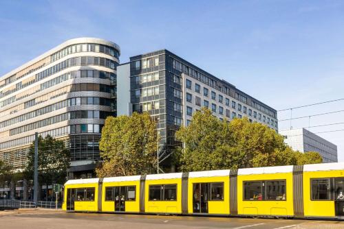 een gele trein geparkeerd voor een gebouw bij Vienna House Easy by Wyndham Berlin Prenzlauer Berg in Berlijn