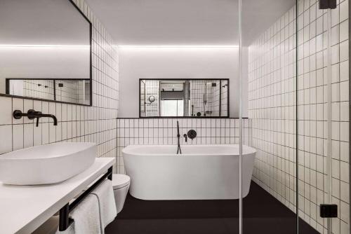uma casa de banho branca com uma banheira e um WC em Vienna House by Wyndham Mokotow Warsaw em Varósvia