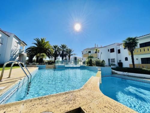 a large swimming pool with palm trees and buildings at Lavanda - 2 Bedrooms - 3 Level Pool - Garden - Beach 1km in Estômbar