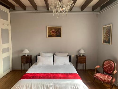 een slaapkamer met een bed en 2 stoelen en een kroonluchter bij Domaine du cheval d’argent 