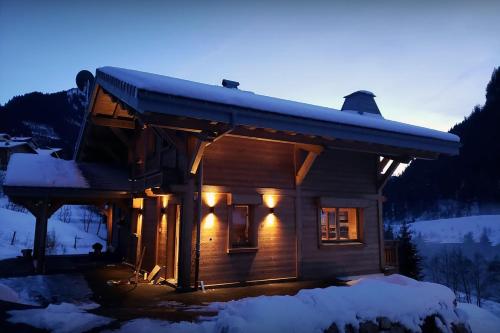 a log cabin with lights on in the snow at Chalet Q - OVO Network in Châtel
