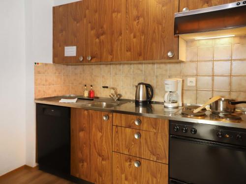 uma cozinha com armários de madeira, um lavatório e um fogão em Apartment Allod-Park-6 by Interhome em Davos
