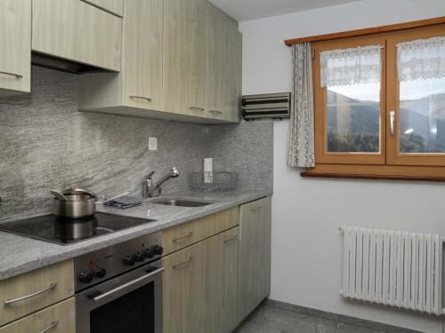 cocina con armarios de madera, fregadero y ventana en Apartment Haus Chumma Apt1 by Interhome en Frauenkirch