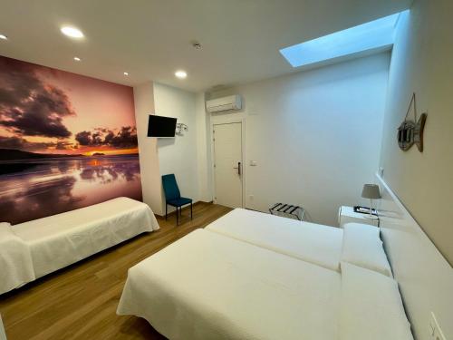 a bedroom with two beds and a painting on the wall at Pensión Txiki Polit in Zarautz
