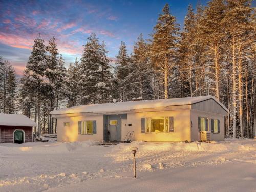 a small house in the snow in front of trees at Holiday Home Rovaniemi ainola by Interhome in Oikarainen