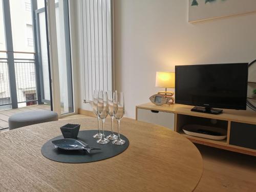 deux verres à vin assis sur une table avec une télévision dans l'établissement Apartment Villa Terre neuve by Interhome, à Saint-Malo