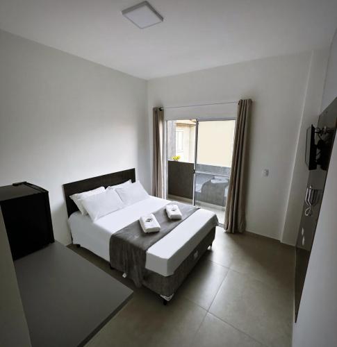 een slaapkamer met een bed en een groot raam bij Hotel Village in São Bernardo do Campo