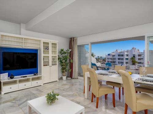 een woonkamer met een televisie en een tafel en stoelen bij Apartment Puerto Marina-2 by Interhome in Benalmadena Costa