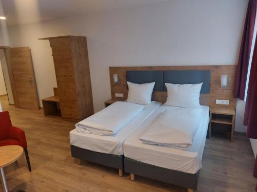 um quarto com uma cama com lençóis brancos e almofadas em Hotel Stern em Gersthofen