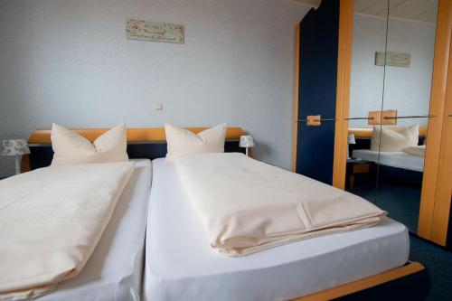 two beds with white sheets and pillows in a room at Hotel Dolgesheim in Dolgesheim