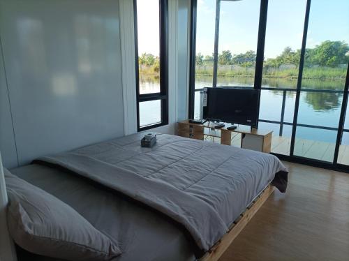 a bedroom with a bed and a flat screen tv at ริมกว๊านชาเลย์ รีสอร์ทแอนด์คาเฟ่ Rimkwan Chalay Resort and Cafe in Ban Rong Ha