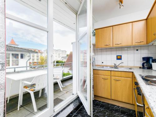 eine Küche mit Holzschränken und einen Balkon mit Aussicht in der Unterkunft Apartment Dünenresidenz 24 by Interhome in Zinnowitz