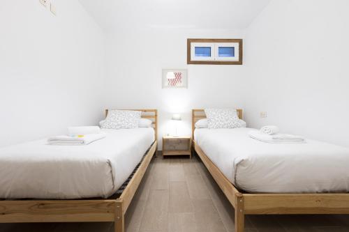 2 camas en una habitación con paredes blancas en ARROLA by Smiling Rentals, en Hondarribia