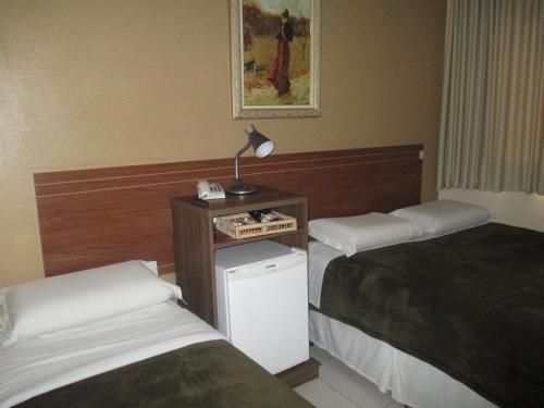 a hotel room with two beds and a lamp on a table at Victor Plaza Formiga in Formiga