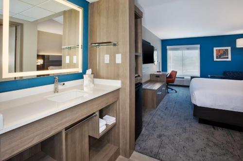 a bathroom with a sink and a bed in a room at Holiday Inn Express Kitty Hawk - Outer Banks by IHG in Kitty Hawk