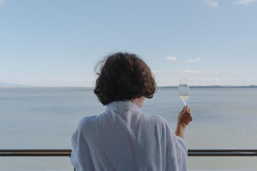 a woman holding a glass of wine looking out a window at Hotel Glamour in Kaluža