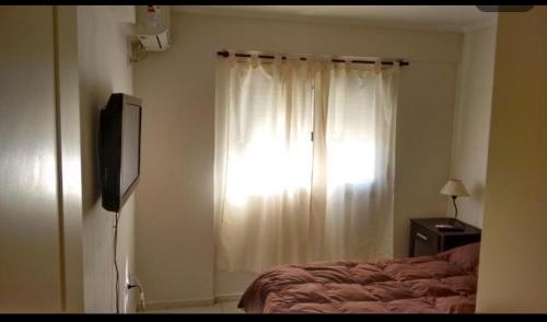 a bedroom with a bed and a window with white curtains at Temporario V sol in Córdoba