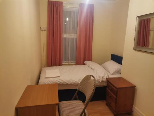 a small room with a bed and a desk and a window at Nice Single Room near London Seven Kings Train station in London