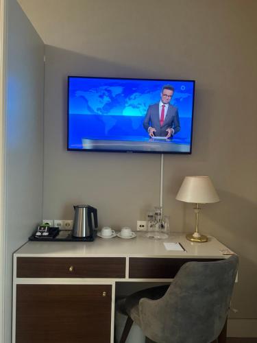 a television on a wall above a desk with a chair at City Hotel Frankfurt Bad Vilbel in Bad Vilbel