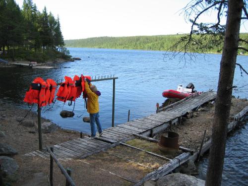 a man standing on a dock next to a body of water at Arctic Island - Remote island, reachable only by boat or snowmobile in Kurravaara